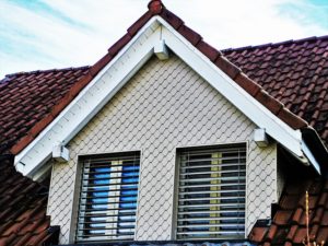 top of an older home showing the roof and windows. 