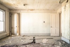 older home with stained walls and destroyed flooring.