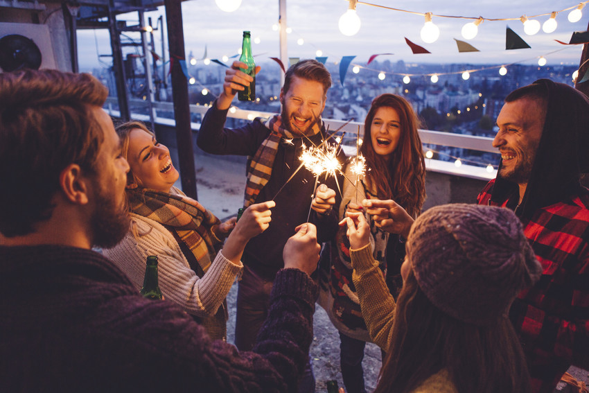 group of friends with sparkles on roof top celebrating new years eve.